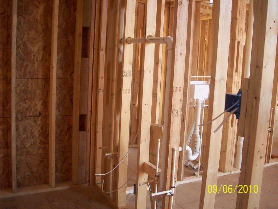 Supply lines and shower valve set in open framing — new-construction plumbing rough-in