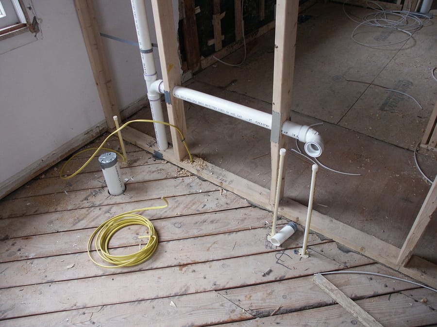 DWV lines and stub-ups run through the subfloor — new-construction plumbing rough-in