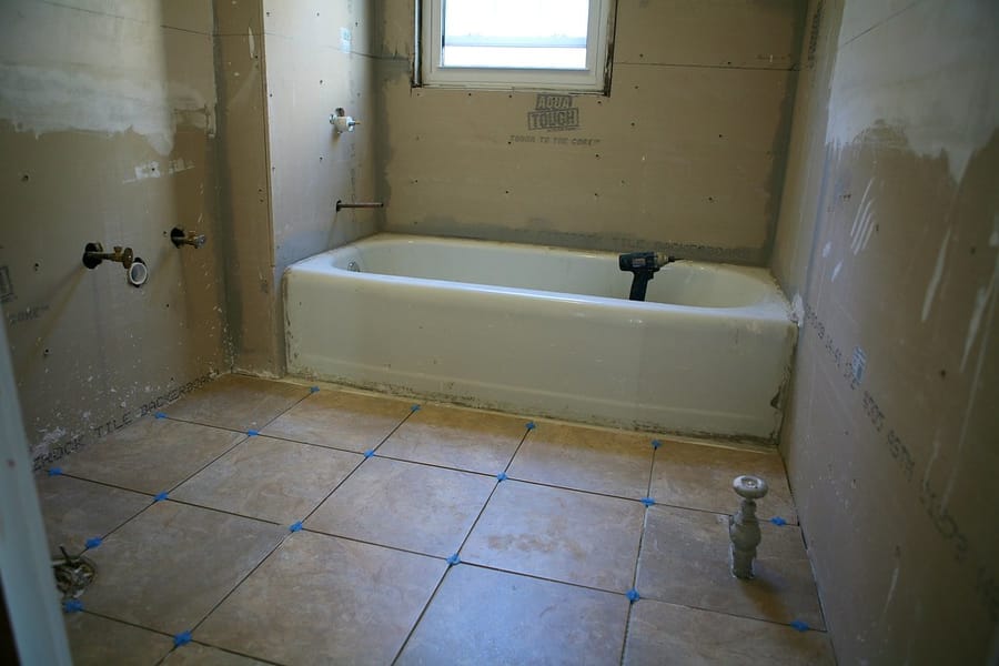 Tub in place, supplies and closet flange ready for finish — new-construction plumbing rough-in